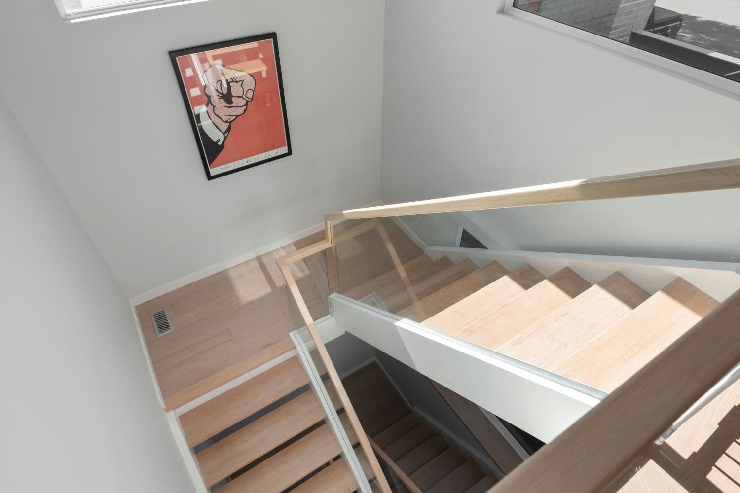 Vue du dessus d’un escalier moderne en bois clair et rampe vitrée