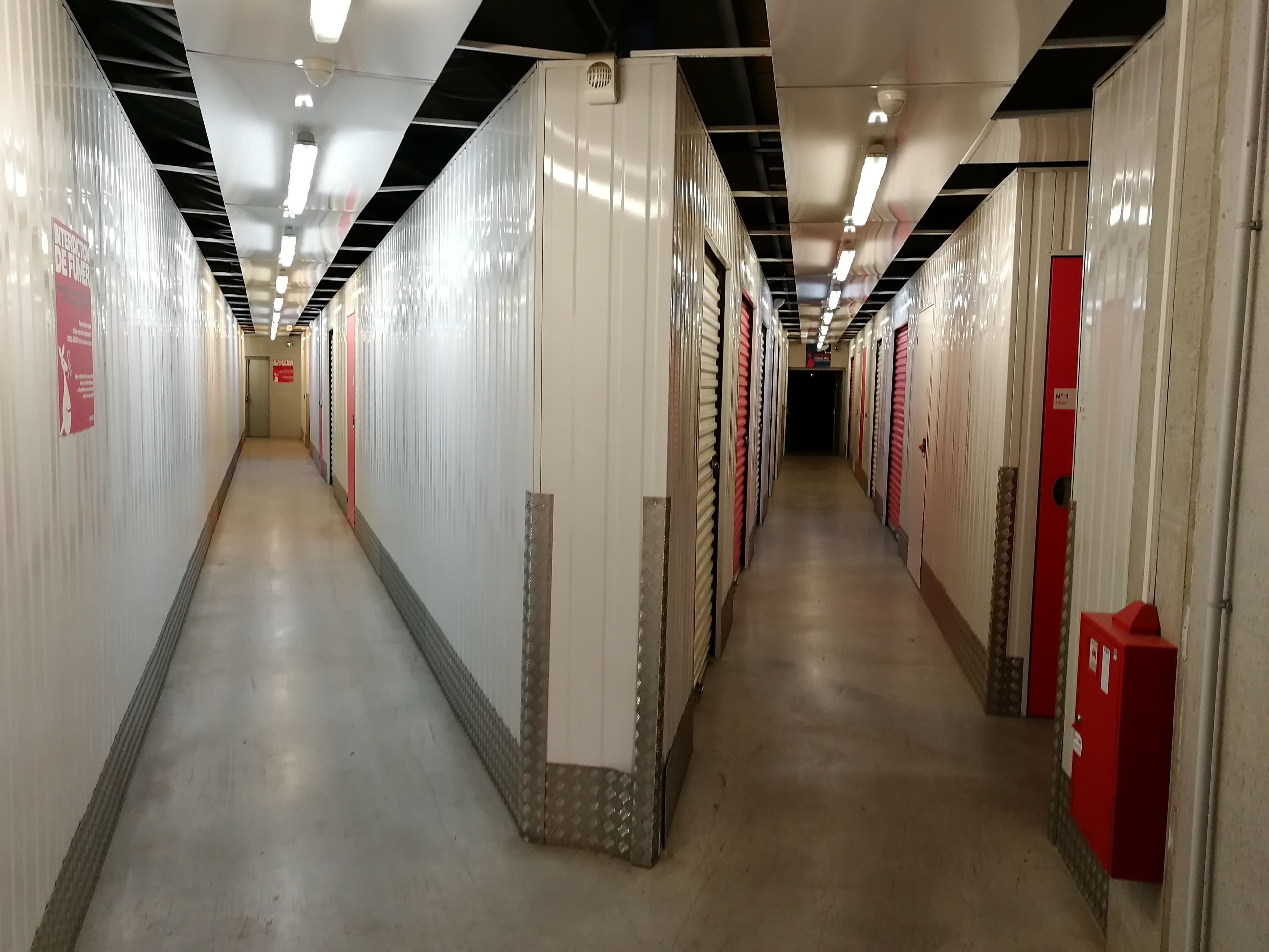 Couloir intérieur du centre HOMEBOX Guérande avec portes roulantes blanches et signalétique rouge.