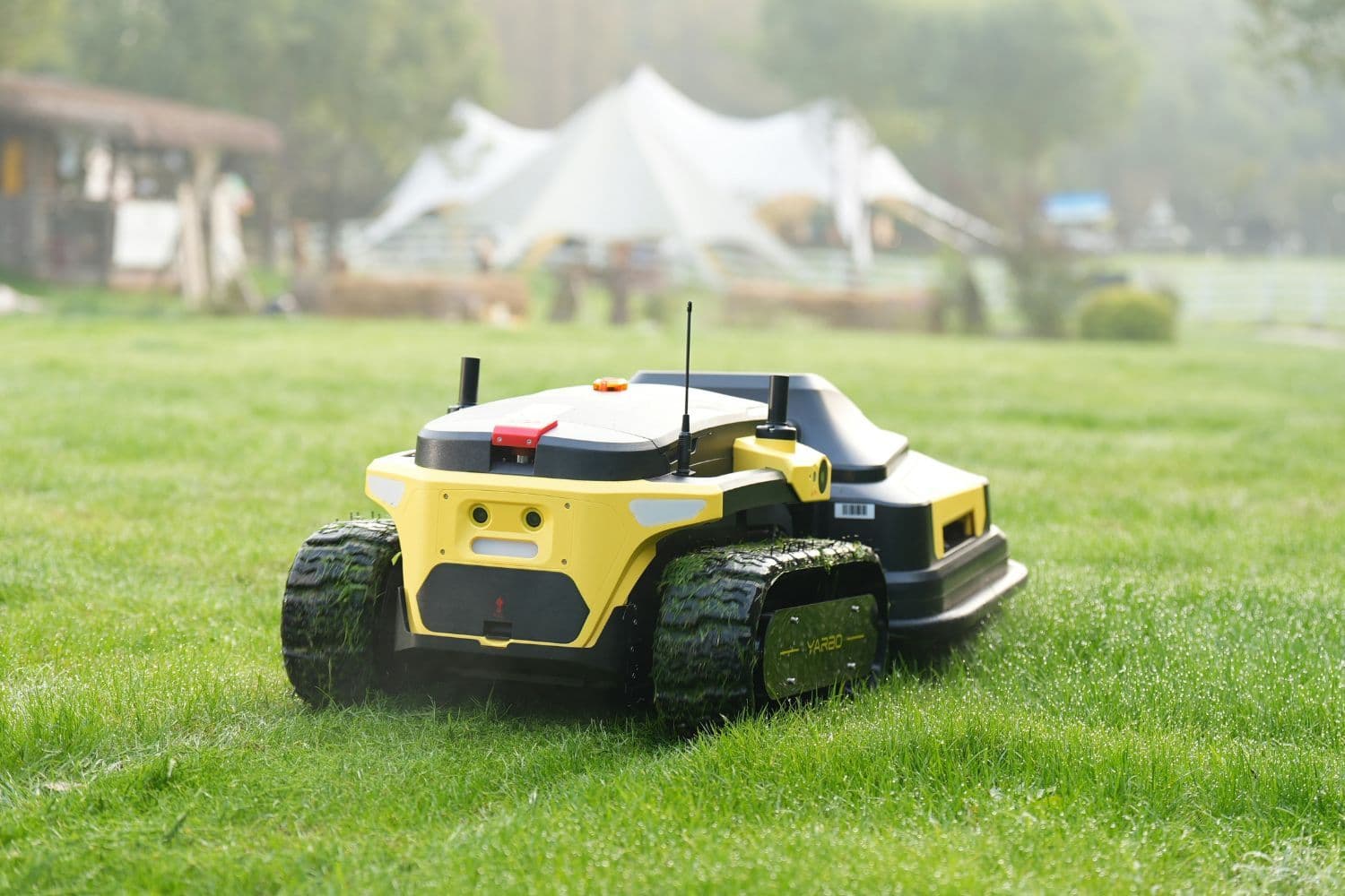 Robot tondeuse noir et jaune en activité au premier plan, tonnelle floue au second plan