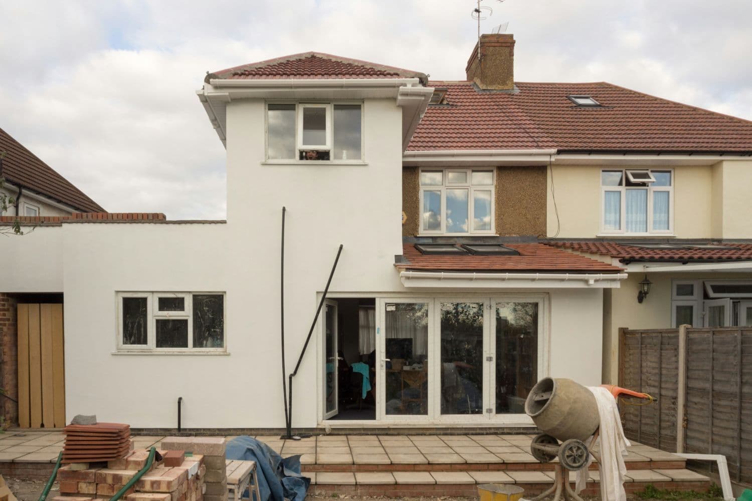 Maison à deux niveaux, toit en briques et bétonnière sur le perron