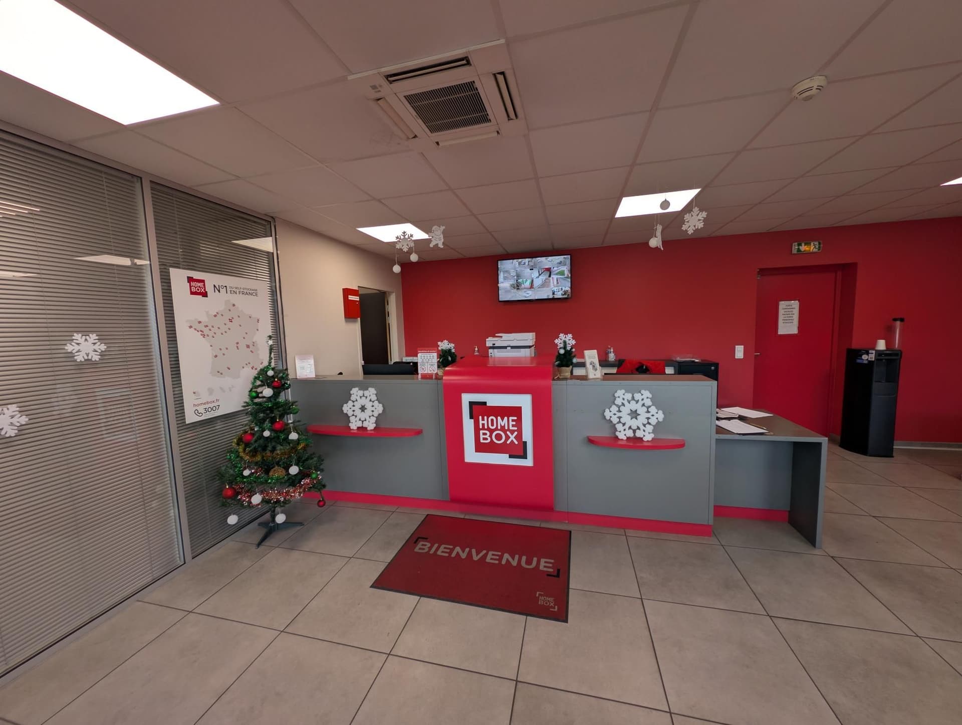 Espace d'accueil avec comptoir rouge, tapis de bienvenue et décoration de Noël du centre HOMEBOX Marseille - Plombières