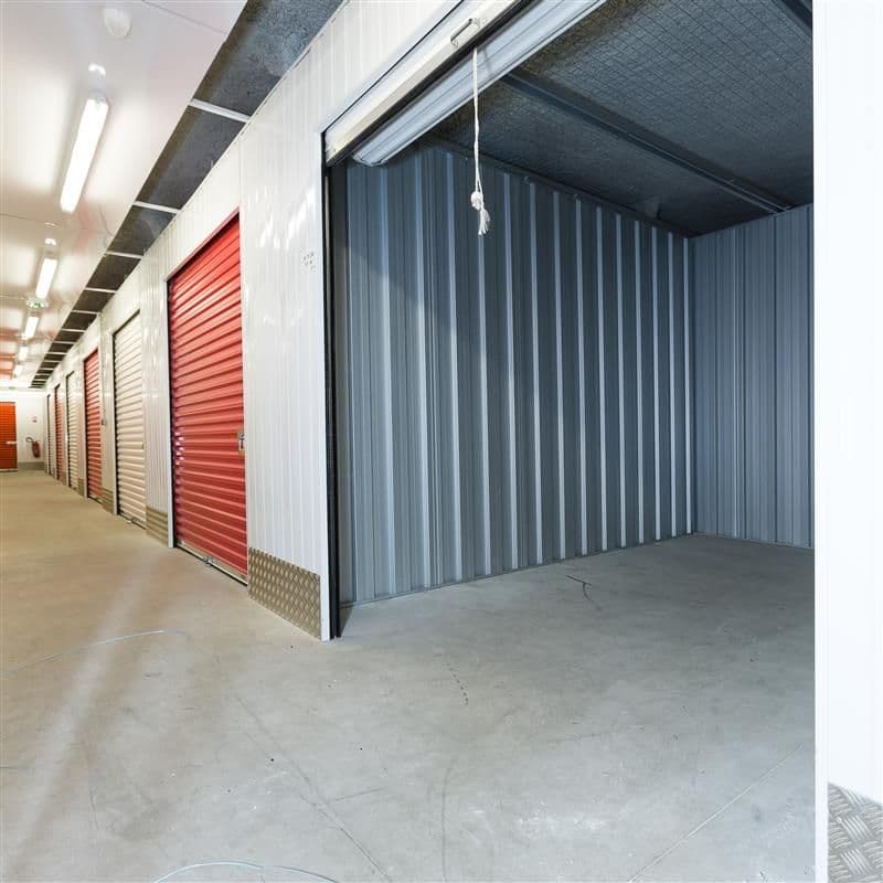 Box intérieur ouvert vide avec porte rouge relevée le long du couloir, HOMEBOX Béthune