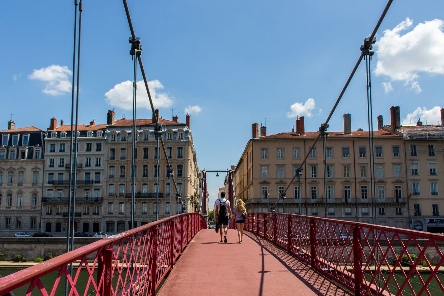 Personne de dos traversant la Passerelle Saint Georges de Lyon par beau temps