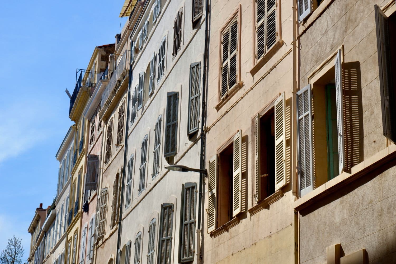 Vue sur les devantures d’immeubles marseillais anciens, fenêtres ouvertes